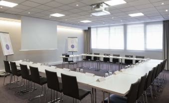 a large conference room with multiple tables and chairs arranged for a meeting or event at Novotel Château de Versailles