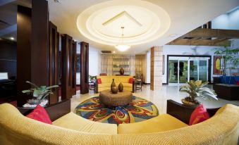 a spacious living room with a large round table in the center , surrounded by chairs and couches at Hodelpa Garden Court
