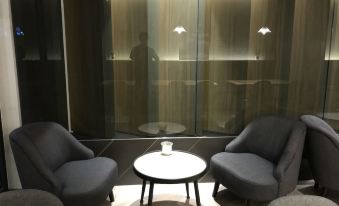 a modern living room with two gray chairs and a round table in front of a large window at Hub Hotel