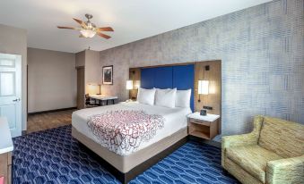 a large bed with a floral comforter is situated in a hotel room with blue walls and blue carpeting at La Quinta Inn & Suites by Wyndham Houston Channelview