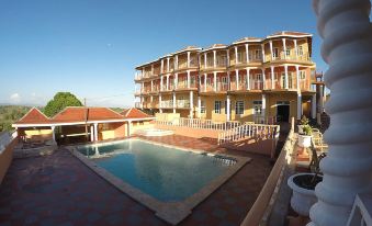 a large swimming pool is surrounded by a red brick patio and a tall building at Paradise Reggae Resort