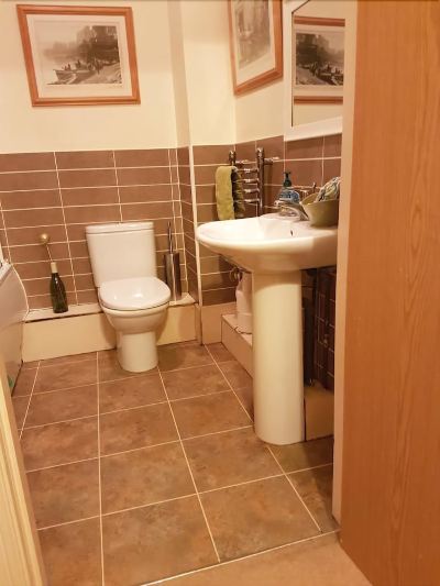 a small bathroom with brown tile flooring , a white toilet , and a sink on a pedestal at Knights