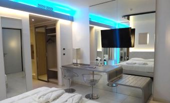 a modern hotel room with a large bed , desk , and tv , reflecting the changing lights on the walls at Hotel Camelia