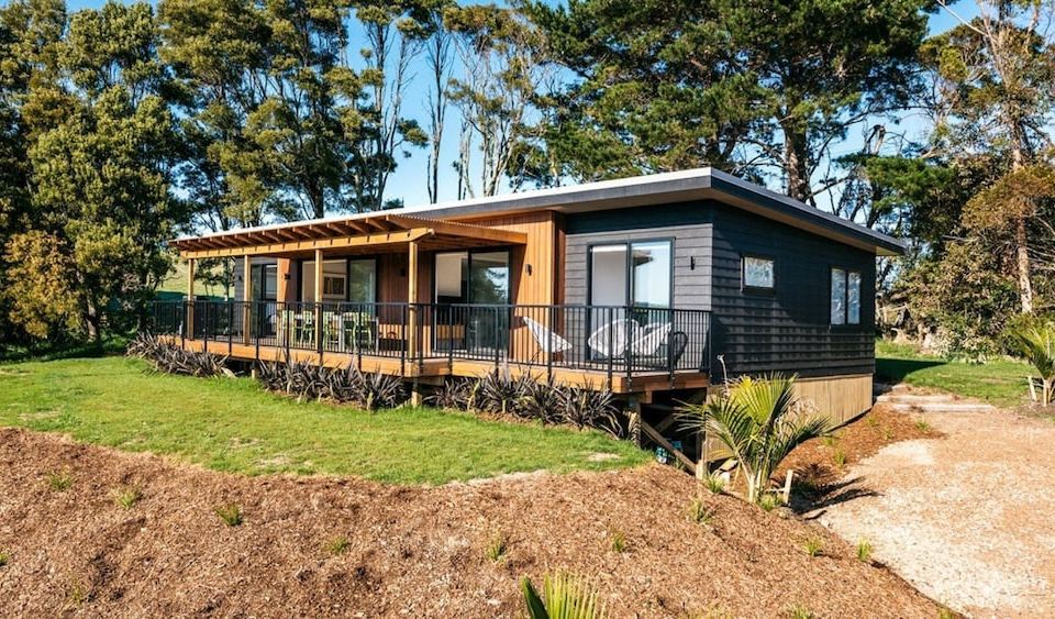 a modern , two - story house with a wooden exterior and large windows , surrounded by trees and greenery at Vineyard Views