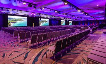 a large conference room with rows of chairs and multiple screens , ready for a meeting or event at Novotel Sunshine Coast Resort