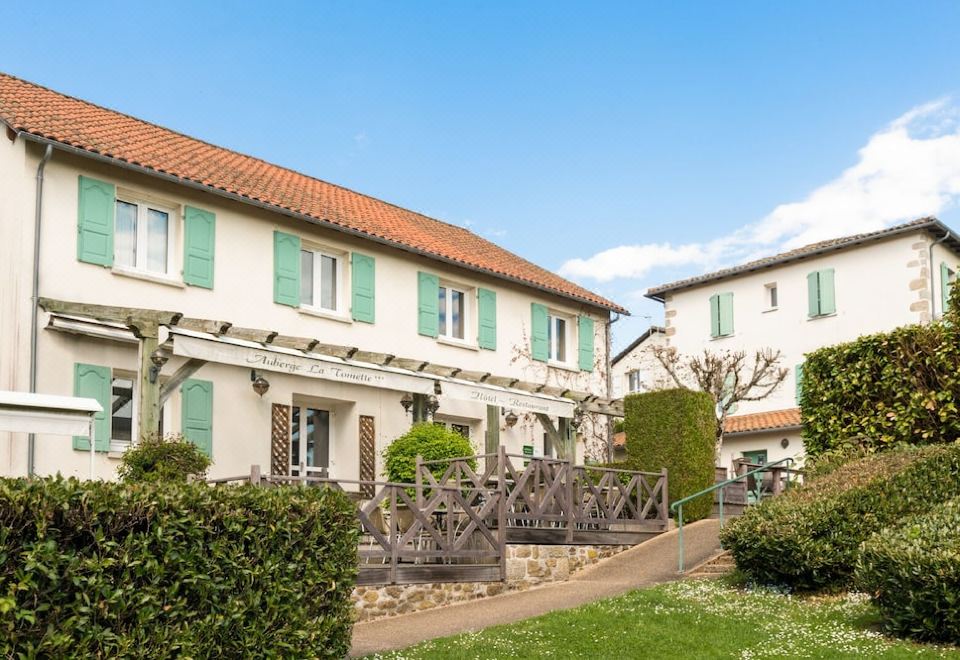 a white house with green shutters and a pergola in front of it , surrounded by a garden at Auberge la Tomette, the Originals Relais