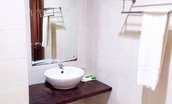 a white sink with a silver faucet is sitting on a wooden counter in a bathroom at Hotel Grand Papua Fakfak