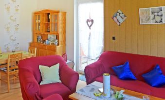 a living room with red chairs and a couch , along with a dining table and chairs at Gila