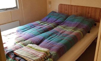 a neatly made bed with a blue and purple striped blanket , two wooden headboards , and a window view at Paradiset