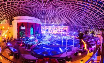 a large , circular room with a crowd of people gathered around a pool at night at Okada Manila