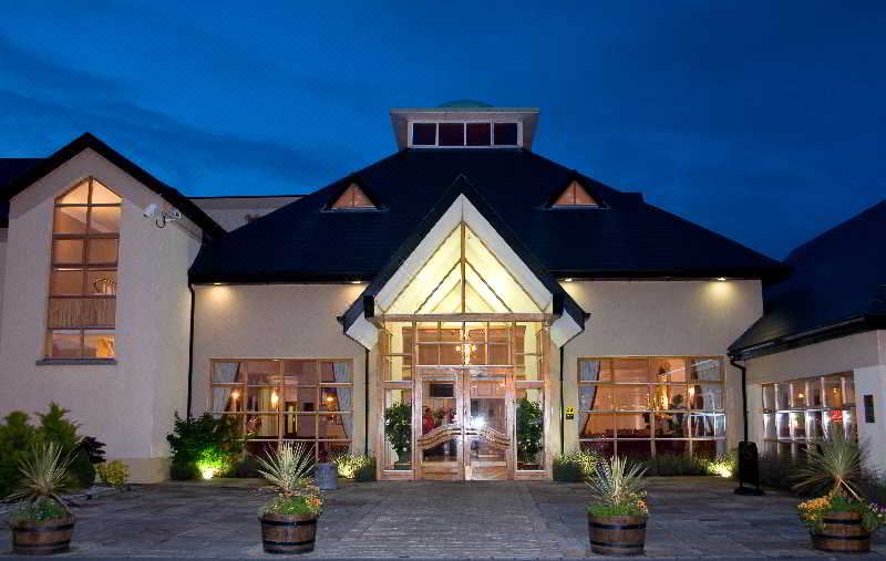 a large building with a triangular roof and glass windows is lit up at night at Clanard Court Hotel