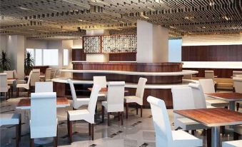 a modern restaurant with white chairs and tables , a bar , and a ceiling made of wood at ASTON Pluit Hotel & Residence