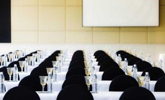 a conference room with rows of tables and chairs , each table has a black cloth and white tablecloth at Robinson Khao Lak