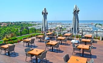 a rooftop patio with wooden tables and chairs , a view of the ocean in the background at Wyndham Grand Istanbul Kalamış Marina Hotel