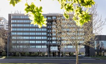 "a modern office building with trees in front of it and the words "" hilton and empire "" on the right side" at Pullman Melbourne Albert Park