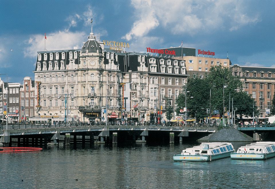 a large building with a boat on the water in front of it , surrounded by water at Park Plaza Victoria Amsterdam