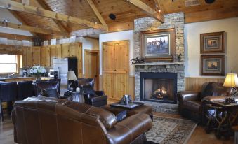 a cozy living room with a fireplace , leather couches , and wooden beams on the ceiling at Mountain Cove Farms Resort