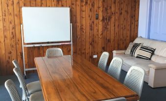 a conference room with a wooden table , chairs , and a whiteboard , set against a wooden wall at Waterview Gosford Motor Inn