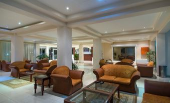 a large , well - lit room with multiple couches and chairs arranged in a comfortable seating area at Poseidon Beach Hotel