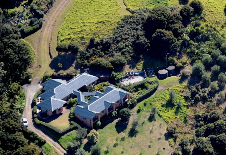 aerial view of a large house surrounded by trees and grass , with a barn in the background at Earthsong Lodge