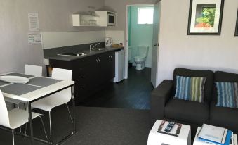 a small , modern kitchen with a sink , microwave , and refrigerator , as well as a living room area with a couch and coffee table at Arrowtown Motel
