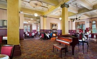 a large room with a piano and people sitting at tables in the center at Jenolan Caves House