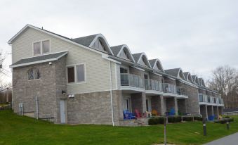 a row of three - story houses with stone and wooden accents , standing next to each other on a grassy slope at Oak Island Resort & Conference Centre