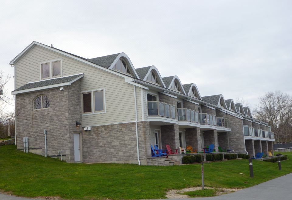 a row of three - story houses with stone and wooden accents , standing next to each other on a grassy slope at Oak Island Resort & Conference Centre