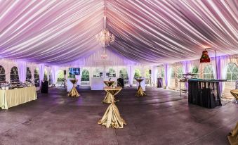 a large , well - decorated tent with multiple tables and chairs set up for an event or gathering at Royal Park Hotel
