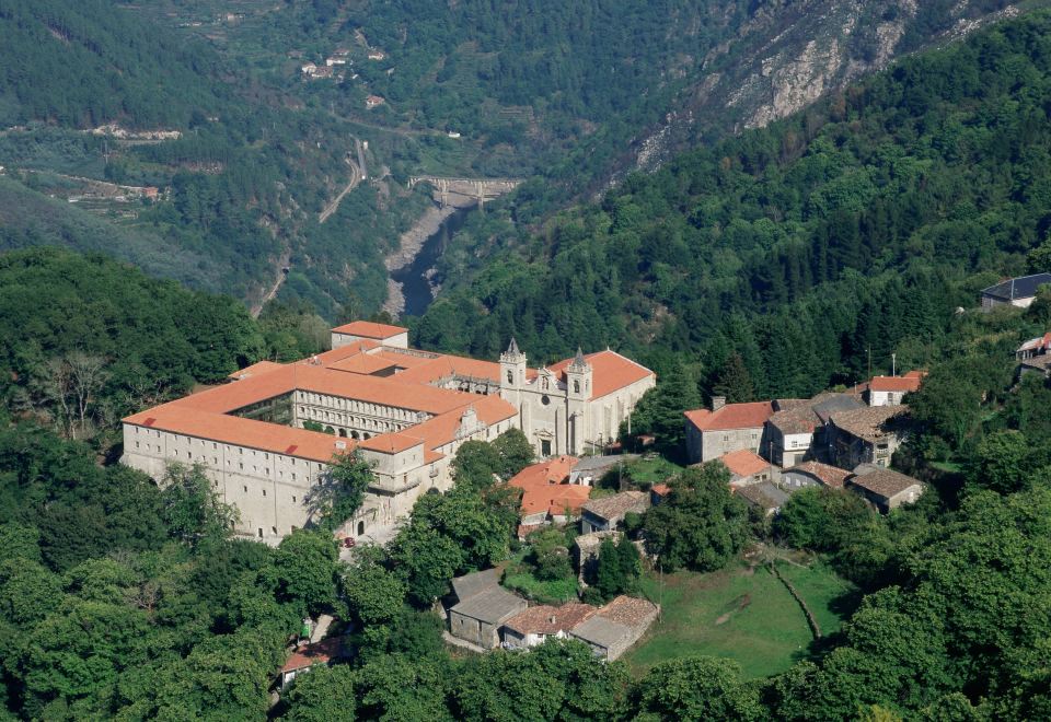 aerial view of a large building surrounded by trees and mountains , located in a forested area at Parador de Santo Estevo