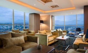 a modern living room with large windows offering a view of the city , featuring comfortable couches and coffee tables at Best Western Premier la Grande Hotel