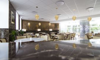 a modern and elegant restaurant with white marble tables , gold pendants , and large windows , giving it an elegant and comfortable atmosphere at A Hotels Glostrup