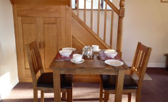 a wooden dining table with two chairs and plates set for a meal , situated in front of a staircase at Orchard House Bed and Breakfast