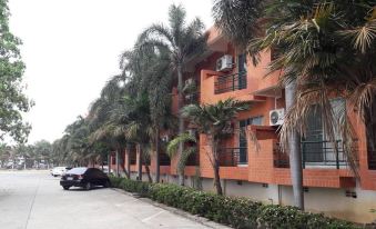 a row of apartment buildings with palm trees lining the street and a car parked in front at Rawanda Resort