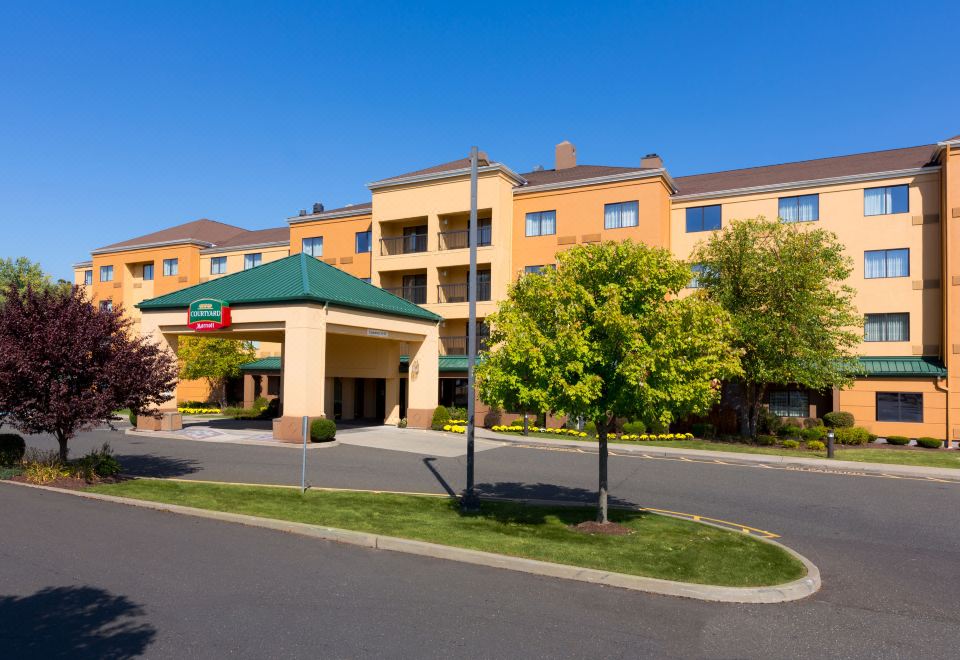 a courtyard by marriott hotel with an orange building and trees , set against a clear blue sky at Courtyard Danbury