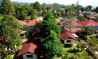 aerial view of a red roofed house surrounded by trees and grass , with a lake visible in the background at Chaolao Cabana Resort