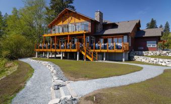 a large wooden house with a large porch and stairs leading up to it , surrounded by trees at Sproat Lake Landing Resort
