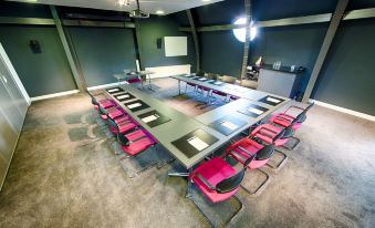 a large conference room with multiple rows of chairs arranged in a semicircle around a long table at Leonardo Hotel Almere City Center