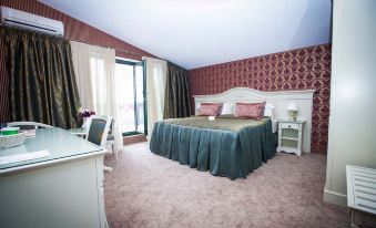 a large bed with a green blanket is in the middle of a room with pink carpeting and beige walls at Savoy Hotel