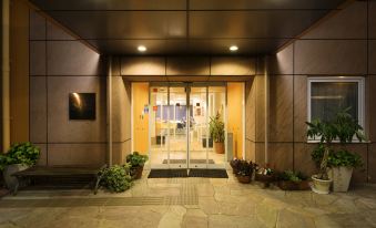 a modern building entrance with stone flooring , glass doors , and potted plants , giving it an inviting atmosphere at Chisun Inn Munakata