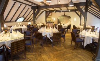 a large , elegant dining room with wooden floors and white tablecloths on the tables , creating a warm and inviting atmosphere at Fletcher Hotel-Restaurant de Klepperman