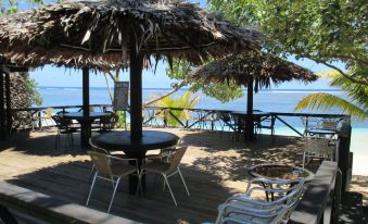 a wooden deck with chairs and a table , surrounded by trees and overlooking the ocean at Stevensons at Manase