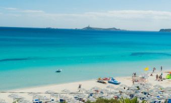 a beautiful beach with clear blue water , white sand , and various people enjoying the sunny day at Hotel Simius Playa