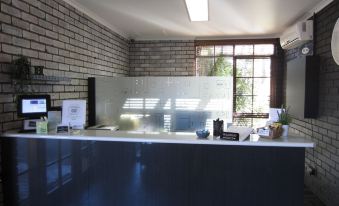 a modern office reception area with a white brick wall , black countertop , and large windows at The Heritage Bendigo