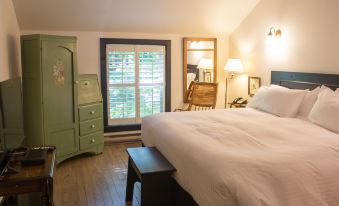a cozy bedroom with a large bed , a dresser , and a window with a view at The Little Inn of Bayfield