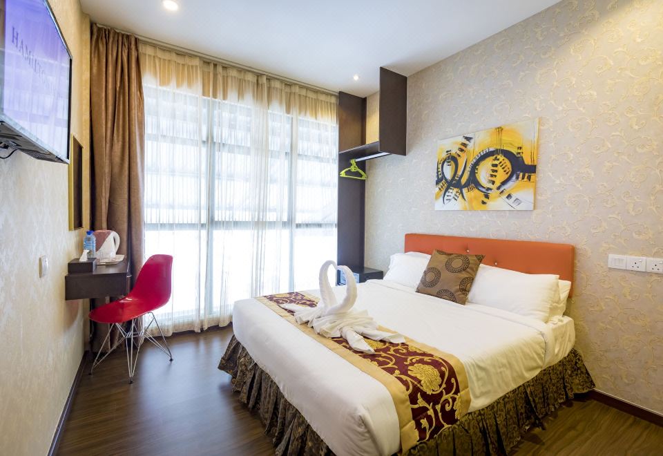 a modern hotel room with a large bed , white curtains , and a colorful abstract painting on the wall at Hamilton Hotel Kajang