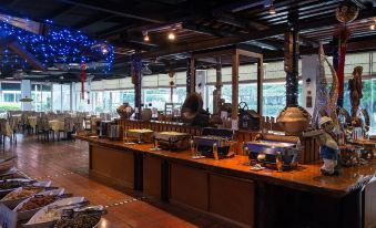 a dining room with a large wooden table and chairs , as well as a buffet table filled with various food items at Rainbow Hotel