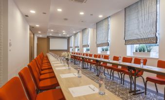 a long conference room with rows of red chairs and a large screen at the front at Hotel Pod Lipou Resort
