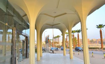 a city street with a white building in the background and palm trees lining the sidewalk at Aracan Pyramids Hotel