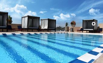 a rooftop pool surrounded by lounge chairs and umbrellas , with a beautiful view of the sky at Grand Hotel Tijuana